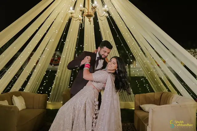 A couple dancing under long fabric drapes and a chandelier, small lights running down every drape.